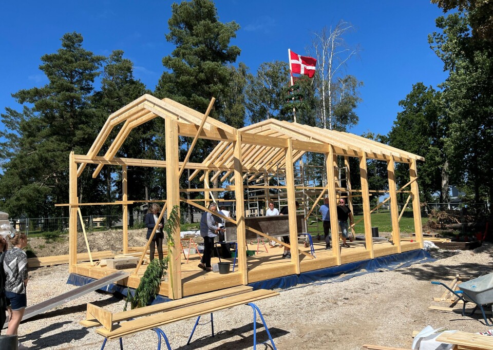 Hampens Hus under opførelse med robotbearbejdede trækonstruktioner og dansk flag